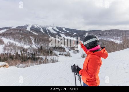 Femme de ski d'hiver.Ski alpin - skieur prenant des photos à l'aide d'un téléphone en regardant la vue sur la montagne contre des arbres enneigés et ski en hiver.Mont Banque D'Images
