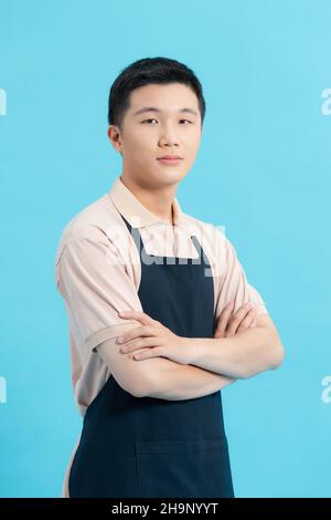 Beau homme en tablier isolé sur fond bleu clair Banque D'Images