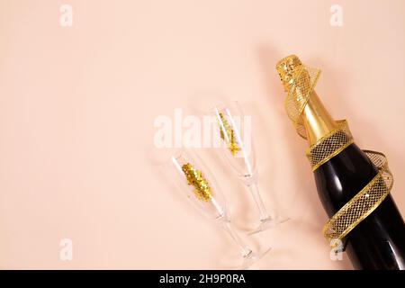 Bouteille de champagne avec verres, rubans dorés et confettis sur fond clair.Concept de Noël, de mariage ou d'anniversaire.Composition de la pose à plat. Espace de copie Banque D'Images