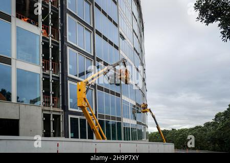 Appartement en construction.Les constructeurs portant des masques de visage travaillant sur une grue jaune, Milford, Auckland. Banque D'Images