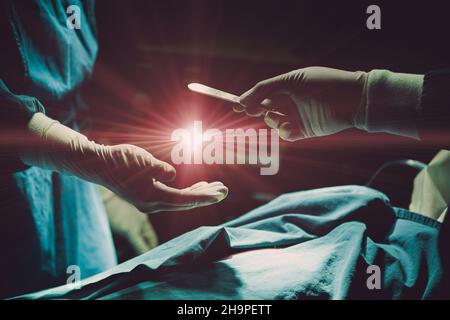 Médecin opérant le patient à l'hôpital envoyant la lame chirurgicale avec la lumière de l'éruption pour donner la vie avec le concept de donneur d'organe. Banque D'Images