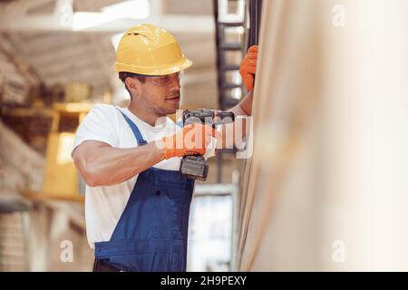 Homme utilisant une perceuse électrique sans fil sur le chantier de construction Banque D'Images