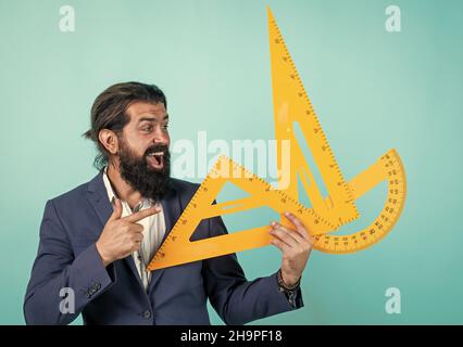 mesure et taille. maître mûr heureux tenant un triangle et un outil de rapporteur. homme barbu ingénieur travaille avec la règle. préparer pour l'examen de géométrie Banque D'Images