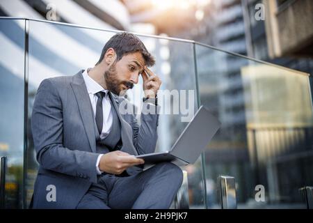 Jeune homme d'affaires frustré travaillant sur un ordinateur portable.Homme d'affaires stressé après l'échec du projet. Banque D'Images