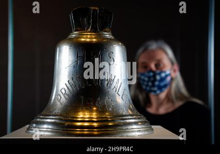 Victoria Ingles, conservateur principal au Musée national de la Marine royale, regarde la cloche du navire du HMS Prince de Galles qui a été coulé avec le HMS Repulse après une attaque aérienne japonaise le 10 1941 décembre.842 hommes ont perdu la vie dans ce qui est l'une des pires catastrophes de l'histoire navale britannique.Date de la photo: Mercredi 8 décembre 2021. Banque D'Images