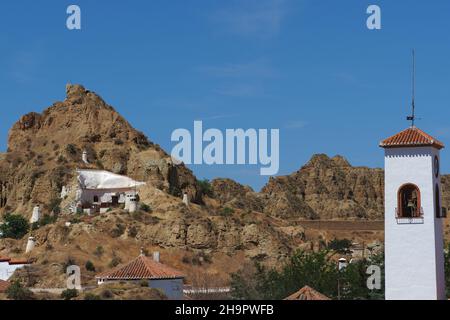 Montagne avec maison de grotte et tour d'église blanche dans le quartier de grotte de Guadix, appartements sur la montagne, roche de tuf calcaire, roche de loess, maisons de grotte Banque D'Images