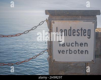 Panneau d'interdiction allemand sur un mur de front de mer: Landesteg - Tauchen verboten. Banque D'Images