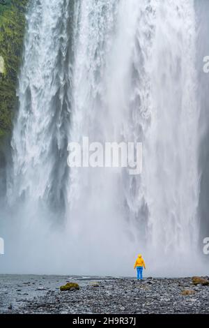 Randonneur devant une énorme cascade, eau tombant sur la falaise, cascade de Skogafoss, Islande du Sud Banque D'Images