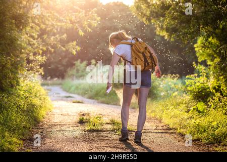 Femme appliquant un insectifuge contre le moustique et la tique sur sa jambe pendant la randonnée dans la nature.Protection de la peau contre les piqûres d'insectes Banque D'Images
