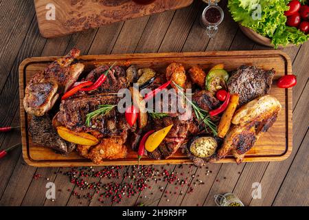 Assortiment de viandes grillées sur un plateau de service en bois Banque D'Images