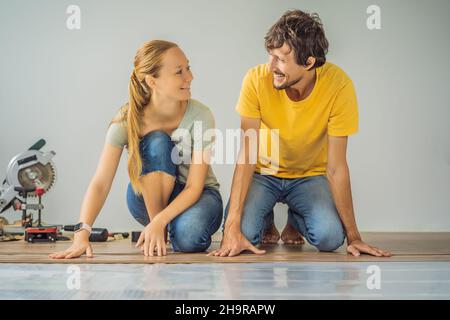 Couple marié installant un nouveau parquet stratifié en bois sur un plancher de film chaud.Système de chauffage au sol infrarouge sous sol stratifié Banque D'Images