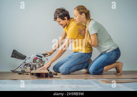 Couple marié installant un nouveau parquet stratifié en bois sur un plancher de film chaud.Système de chauffage au sol infrarouge sous sol stratifié Banque D'Images