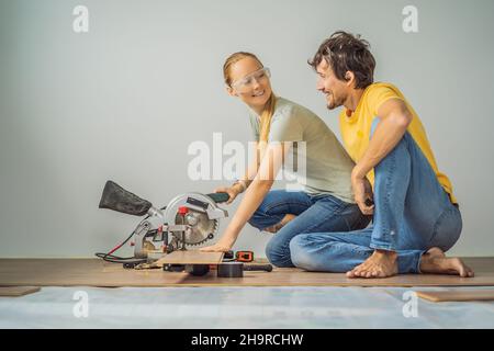 Couple marié installant un nouveau parquet stratifié en bois sur un plancher de film chaud.Système de chauffage au sol infrarouge sous sol stratifié Banque D'Images