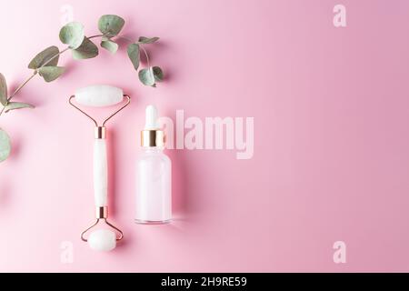 Composition d'une bouteille de sérum maquette blanche, rouleau frontal en pierre de quartz rose sur fond rose.Concept de cosmétiques naturels.Maquillage de maquillage créatif plat avec humour Banque D'Images