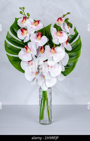 Un bouquet de fleurs dans un vase, des orchidées blanches dans une bouteille de verre sur une table grise.Décoration intérieure.Fleurs encore en vie, carte de vœux, composi d'été Banque D'Images
