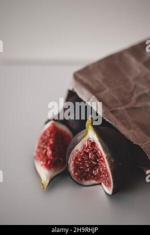 Récolte de fruits frais de figues mûres entières et coupées en deux, sur le papier brun artisanal Banque D'Images