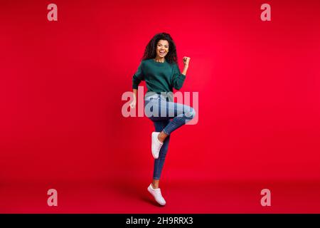 Photo pleine grandeur de la jeune femme afro-américaine positive gagnante bonne humeur isolée sur fond rouge Banque D'Images
