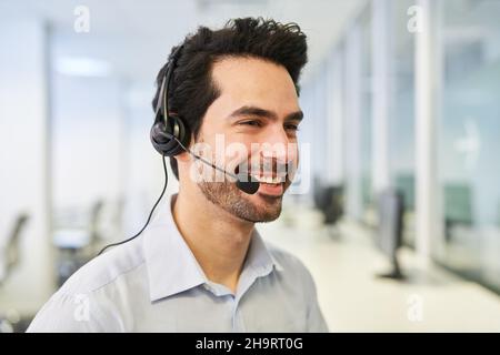 Homme d'affaires souriant avec micro-casque en tant que représentant du service clientèle ou conseiller au centre d'appels Banque D'Images