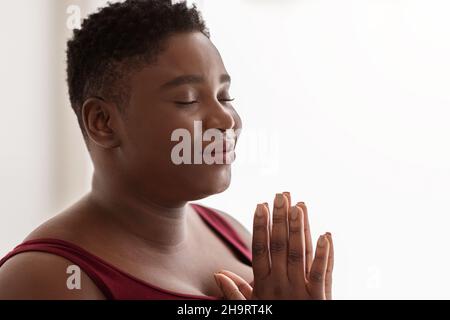 Gros plan portrait de la paisible chubby femme noire méditant Banque D'Images