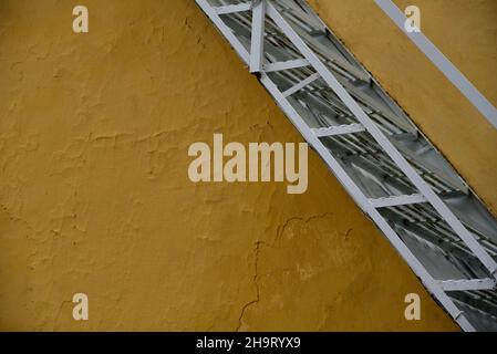 Escalier traditionnel en métal fait sur mesure contre un mur texturé ocre à Nafplio, Grèce. Banque D'Images