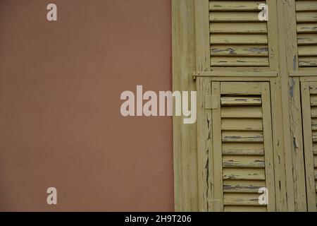 Ancienne maison de campagne traditionnelle avec des volets en bois jaune de maïs contre un mur en stuc de pêche à Nafplio, Grèce. Banque D'Images
