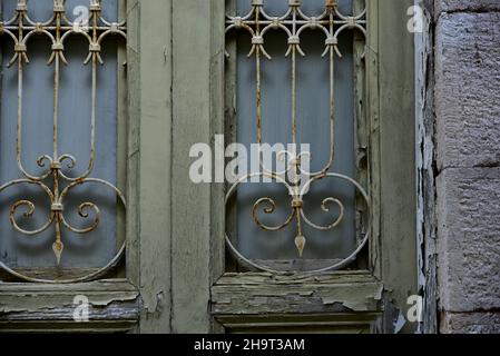 Ancienne maison néoclassique ancienne porte en bois avec grilles en fer rouillé contre un mur en pierre à Nafplio, Grèce. Banque D'Images