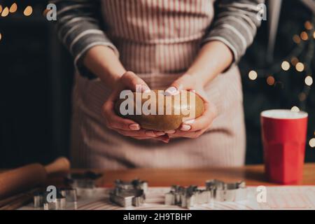 Joyeux Noël, Bonne Année.Cuisson au pain d'épice, gâteau, biscuit ou strudel.La femme en tablier pétrit la pâte.Fille tenant doucement, les faux plis, cuire et cuire au four.Décorations de Noël dans la cuisine Banque D'Images