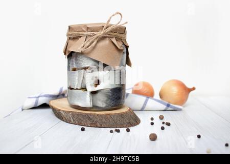 Poisson de hareng mariné avec poivre dans un pot sur la table sur fond clair Banque D'Images