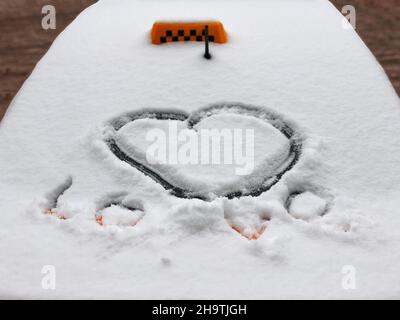 Gros plan de coeur de neige dessiné et mot Amour sur la cagoule de voiture de taxi, froid hiver jour Banque D'Images