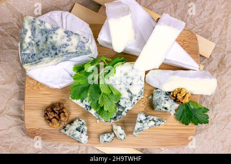 Vue de dessus de nombreuses variétés différentes de fromage: Bleu, brie, camembert et autres avec des noix sur fond de bois. Banque D'Images