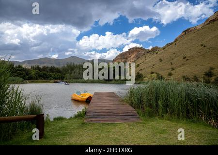 Paysage scène d'une jetée en bois avec un bateau à aubes jaune à côté dans un lac.Il y a des nuages dans le ciel Banque D'Images