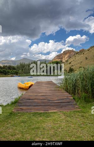 scène verticale de pays d'une jetée en bois avec un bateau à aubes jaune à côté d'elle dans un lac Banque D'Images