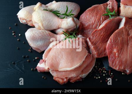 Divers types de viande fraîche : porc, bœuf et poulet sur une table noire Banque D'Images