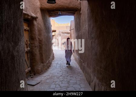 Saoudien marchant dans l'étroite rue couverte du village du patrimoine d'Ushaiqer, Arabie Saoudite. Banque D'Images