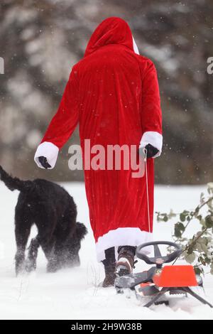 '09.02.2021, Allemagne, , Berlin - le Père Noël tire son traîneau derrière lui accompagné d'un chien.00S210209D476CAROEX.JPG [AUTORISATION DU MODÈLE : NON, PROPRIÉTÉ R Banque D'Images