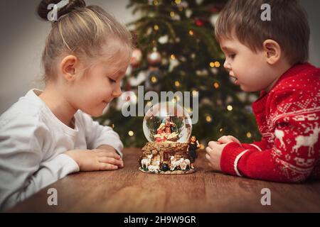 Enfants regardant une boule de verre avec une scène de la naissance de Jésus-Christ Banque D'Images