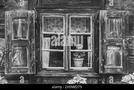 Prise de vue en niveaux de gris d'une ancienne cabine en bois avec réflexion d'une personne dans la vitre Banque D'Images