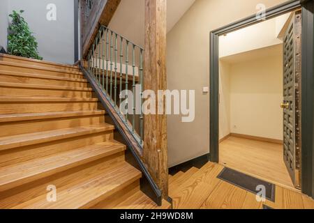 Entrée à une maison avec une ancienne porte lambrissée peinte en vert mat et des escaliers en pin avec des colonnes en bois Banque D'Images