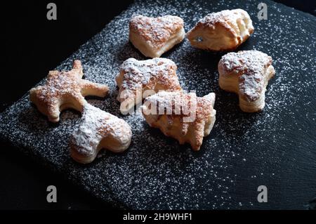 savoureux fond de gâteaux à la cannelle de pâte feuilletée sur fond d'ardoise noire, saupoudrés de sucre en poudre Banque D'Images