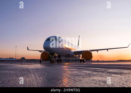 Avion de ligne moderne sur le tablier de l'aéroport avec un coucher de soleil panoramique Banque D'Images