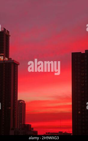 Incroyable ciel rouge corail éclatant avec coucher de soleil sur la silhouette des gratte-ciels Banque D'Images