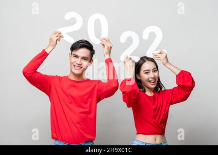 Jeune couple asiatique souriant montrant le numéro 2022 dans un fond gris clair isolé pour le nouveau concept d'année Banque D'Images