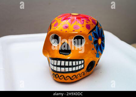 Crâne humain peint en orange avec des fleurs pour la Journée des morts du Mexique sur fond de couleur, mise au point sélectionnée. Banque D'Images