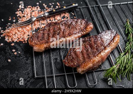 Rôti de chapeau grillé au barbecue ou bifteck de bœuf au sirloin du haut, viande frite sur le gril.Arrière-plan noir.Vue de dessus Banque D'Images