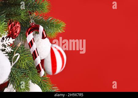 Décoration d'arbre de Noël en forme de canne à sucre suspendue à la branche devant un fond rouge Banque D'Images