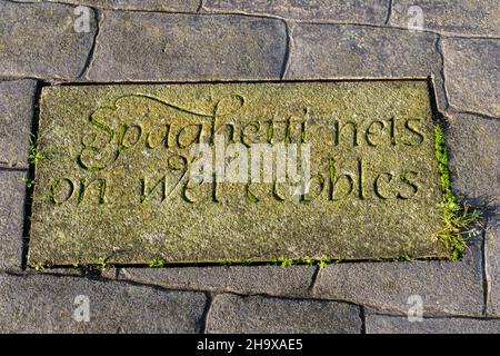 Dalle de pierre sculptée dans le mur du port de Maryport avec les mots « filets de paghetti sur les pavés humides », Cumbria, Angleterre, Royaume-Uni Banque D'Images