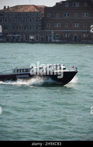 Un bateau de police en Italie rougit le long de la rivière avec des vagues, en arrière-plan deux bâtiments anciens Banque D'Images