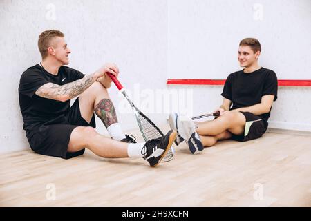 Portrait complet de deux garçons sportifs, joueurs de squash se reposant après un jeu d'équipe productif Banque D'Images