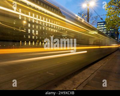 Lumières d'un tramway en mouvement au crépuscule dans St Peters Square Manchester Greater Manchester England Banque D'Images