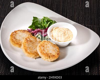 portion de patties de poulet sur une assiette servie avec un mélange de salade et une sauce mille île, photo sur fond sombre Banque D'Images